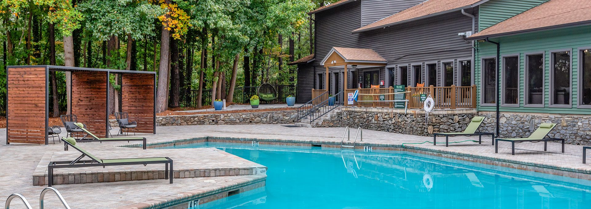 a pool in the woods with lounge chairs and a fire pit at The  Breck